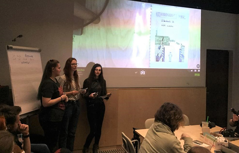 Drei Schülerinnen präsentieren den gemeinsam gestalteten Comic.