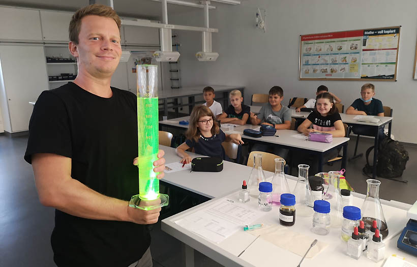 Fachlehrer für Chemnie der DPFA-Reenbogen-Schulen Zwickau präsentiert ein hohes Glas mit einer rotierenden, grünen Flüssigkeit.