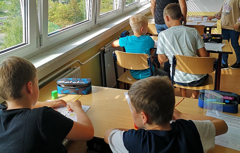 Schülerinnen und Schüler sitzen gemeinsam in ihren Bänken der DPFA-Regenbogen-Schulen zwickau und lösen Aufgaben.