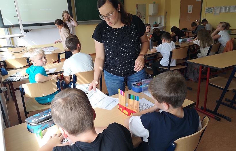 Geschichtslehrerin Stephanie Albrecht steht an einem der Tische im Klassenraum der DPFA-Regenbogen-Schulen Zwickau und hilft zwei Schülern beim Lösen ihrer Aufgaben.